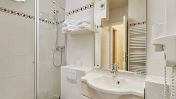 A modern bathroom with a glass shower enclosure, a white sink, and a mirror with a towel rack above it.