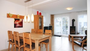 A dining area with a wooden table and chairs, a wooden cabinet, and a fireplace. - Doppelhaushalfte Rugentraum in Glowe (Glowe)