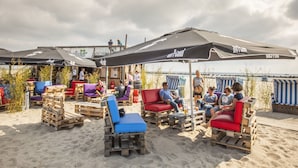 Outdoor seating with umbrellas, wooden furniture, and a beachside view. - Holiday Home in Damp With Garden (Damp)
