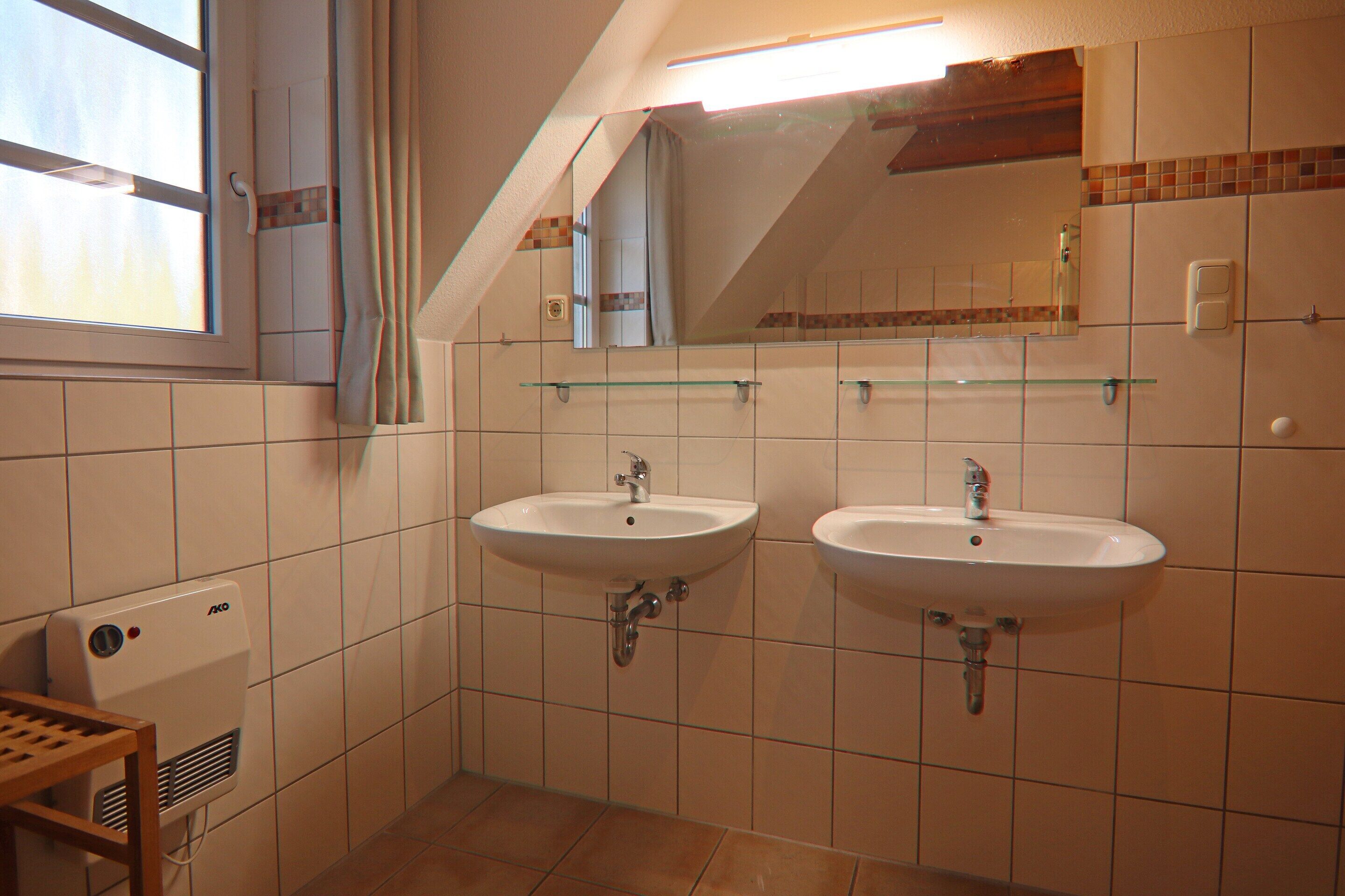 Une salle de bain avec deux lavabos, une fenêtre et un miroir.