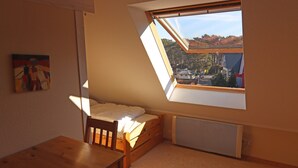Une petite pièce chaleureuse avec un plafond en pente, un lit simple, une table en bois et un radiateur.