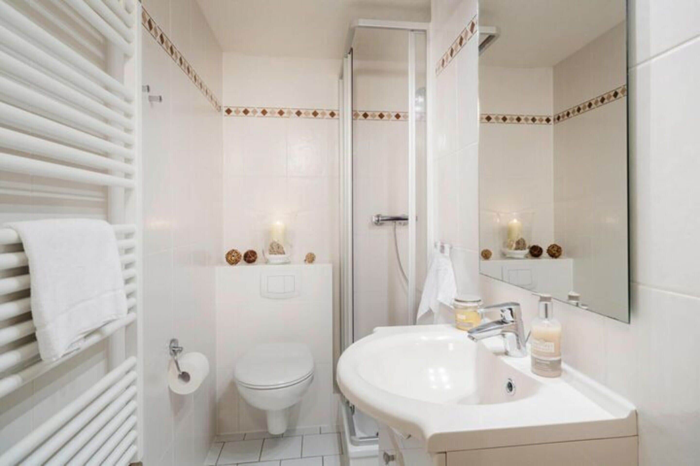 Un bagno moderno con lavandino, water e doccia bianchi.