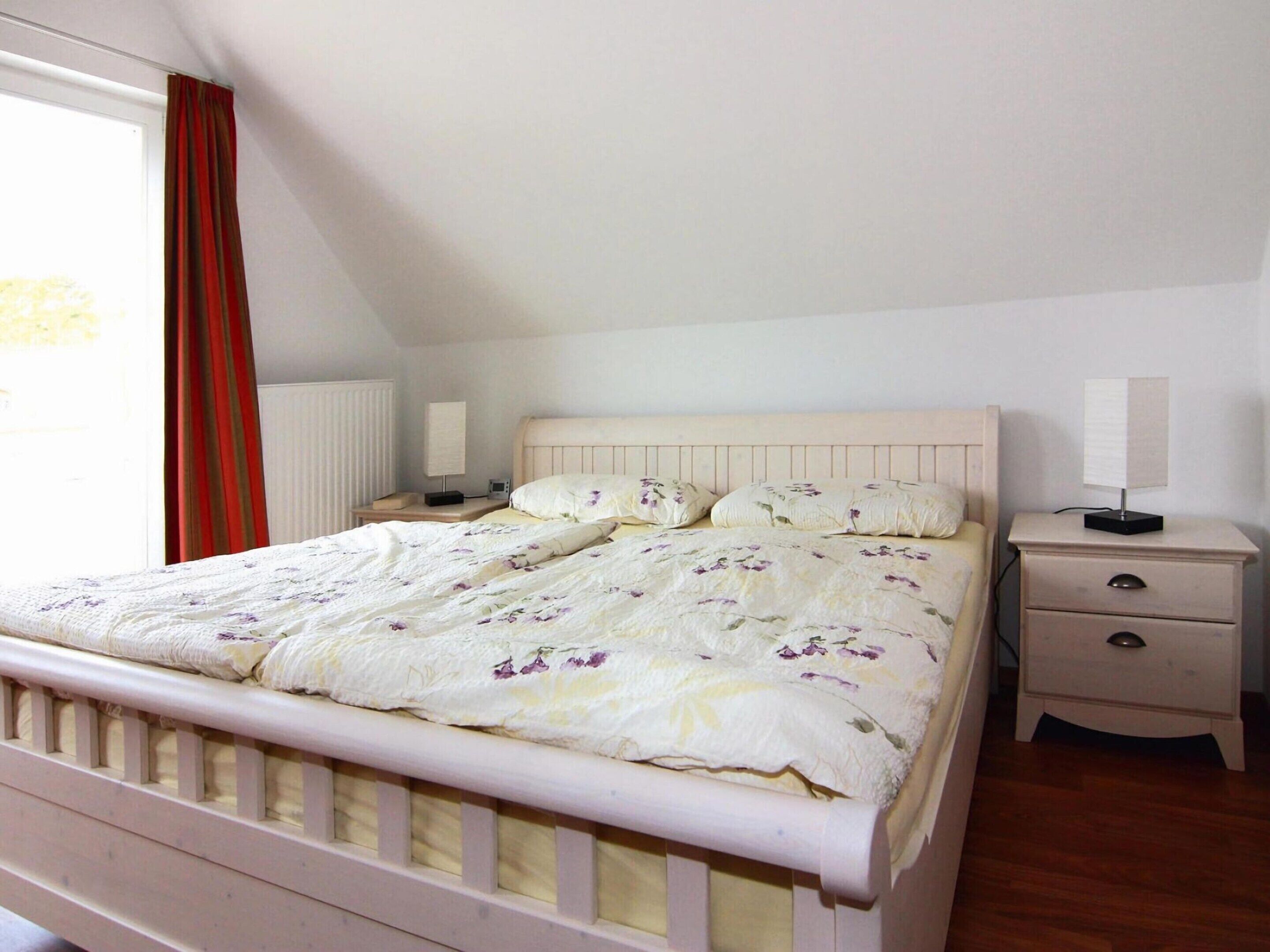 Une chambre à coucher avec un lit, deux tables de chevet et une fenêtre avec des rideaux.