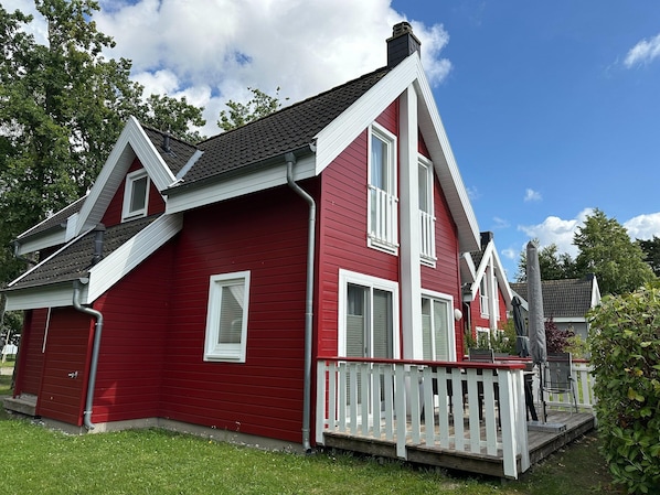 A red house with a white porch and a chimney.