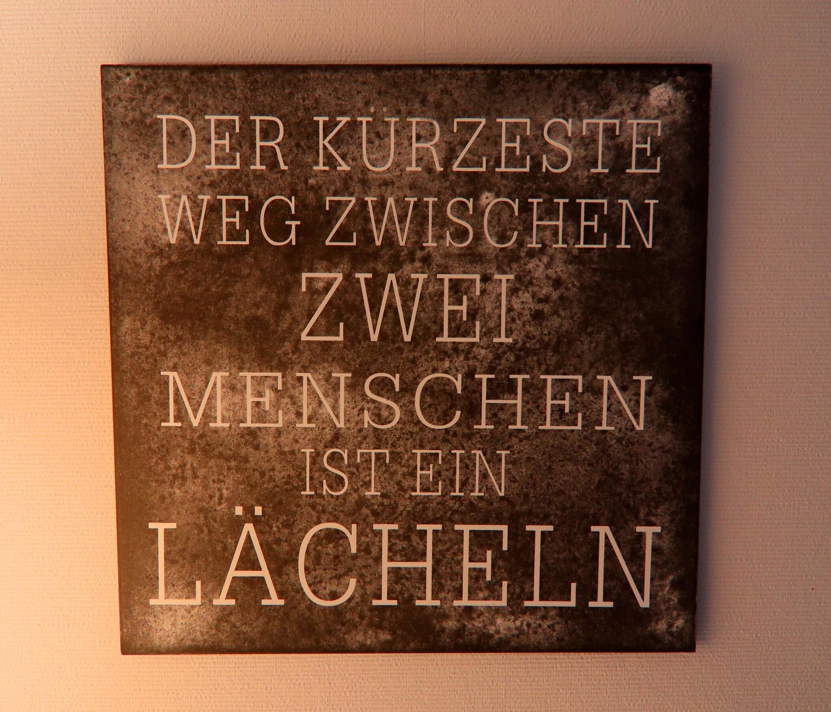 A sign with text in German on a textured background.