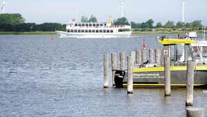 Een rivier met een veerpont en een aangemeerd schip.