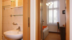 Een badkamer met een wastafel, spiegel en een douchecabine met glazen wanden.