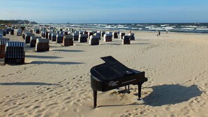 Een strand met vele strandstoelen en een vleugelpiano op de voorgrond.