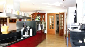 Une cuisine moderne avec des meubles de couleur rouge, des appareils électroménagers en acier inoxydable et un plancher en bois.