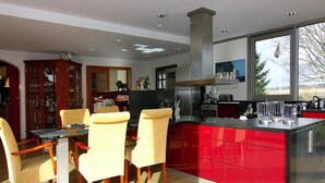 Une cuisine moderne avec un îlot central rouge, des chaises en bois et une table à manger.