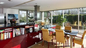 Une cuisine moderne avec un coin repas, de grandes fenêtres et une vue sur l’extérieur.