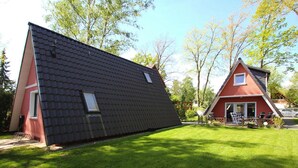 Una casa moderna con tetto spiovente, facciata rossa e prato curato.