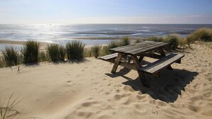 A beach with a wooden picnic table and sand dunes. - Ferienhaus am Watt, List auf Sylt (List)