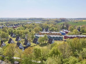 A residential area with multiple houses, some with sloped roofs and others with flat roofs, surrounded by greenery and trees. - Ferienhaus im Ostseebad Dampland (Damp)