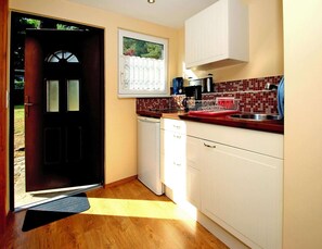 Enjoy cooking in this well-equipped kitchen with a dishwasher, sink, and tiled backsplash.