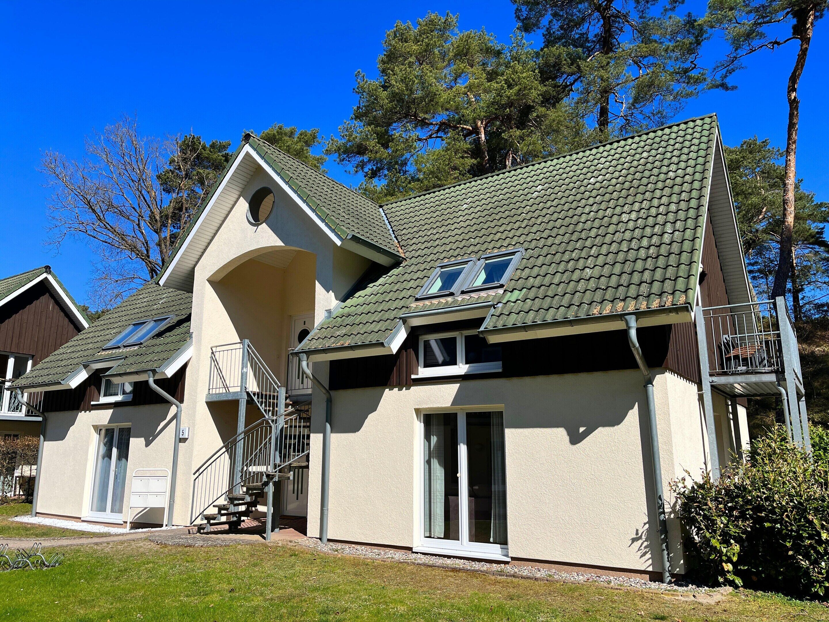 A two-story building with a green roof, a balcony, and a staircase leading to an upper floor.
