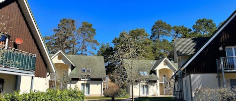 A row of cabins with a gravel path, surrounded by greenery and trees.