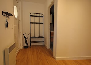 A room with a radiator, a mirror, a black metal shelf, and a door leading to another room. - Moderne Ferienwohnung Strandidyll, Trassenheide (Trassenheide)