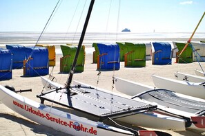 Une rangée de voiliers sur une plage de sable, avec une mer calme en arrière-plan.
