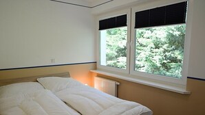 A bedroom with a bed, a window with blinds, and a radiator. - Ferienwohnung in Wyk auf Foehr (Wyk auf Foehr)