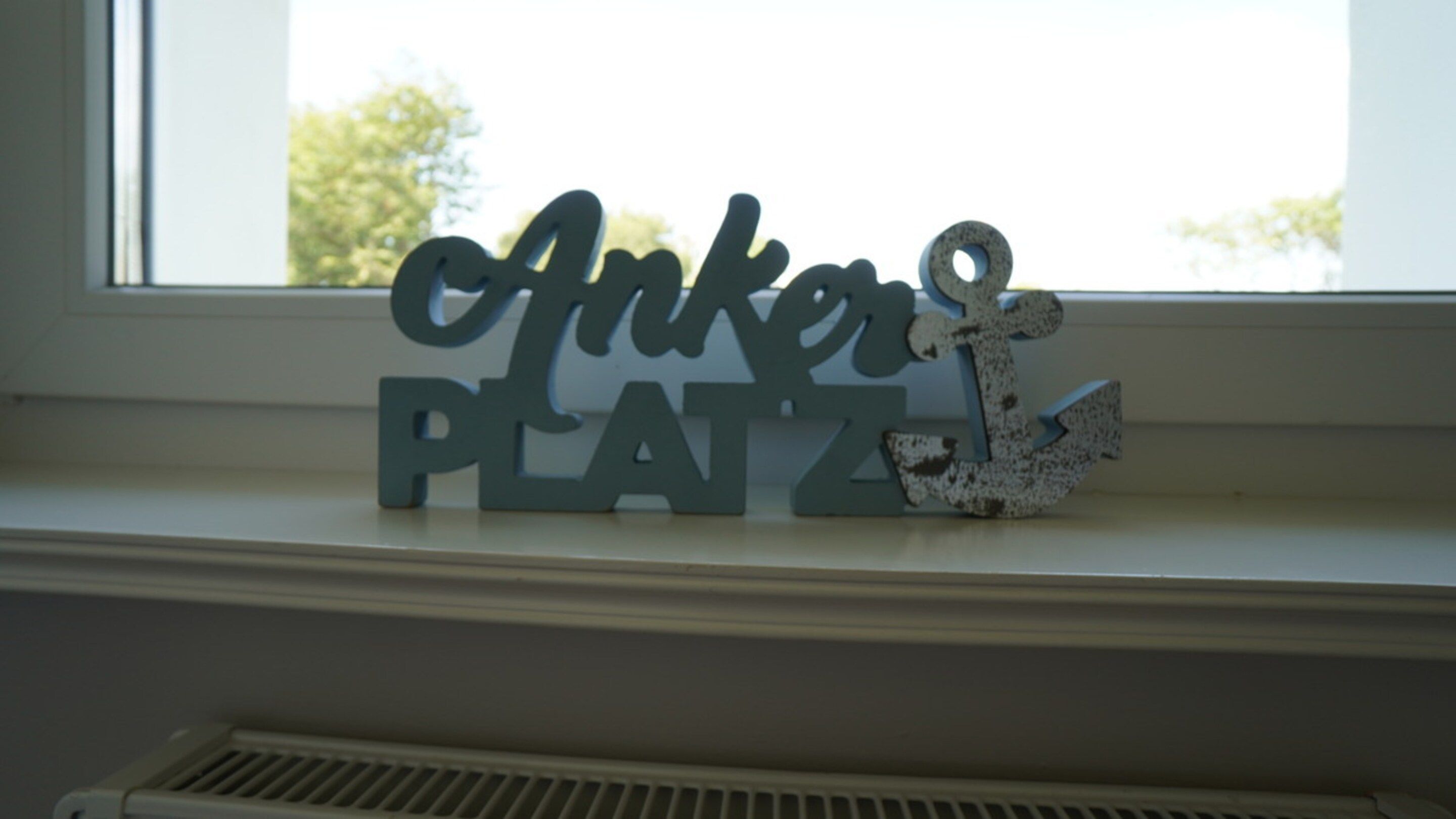 A decorative sign with the words 'Anker Platz' on a window sill.