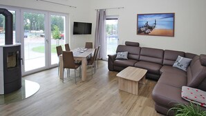 A modern living room with a sofa, a dining table, chairs, a TV, and a fireplace. - Appartement Hafenflair am Plauer See (Plau am See)