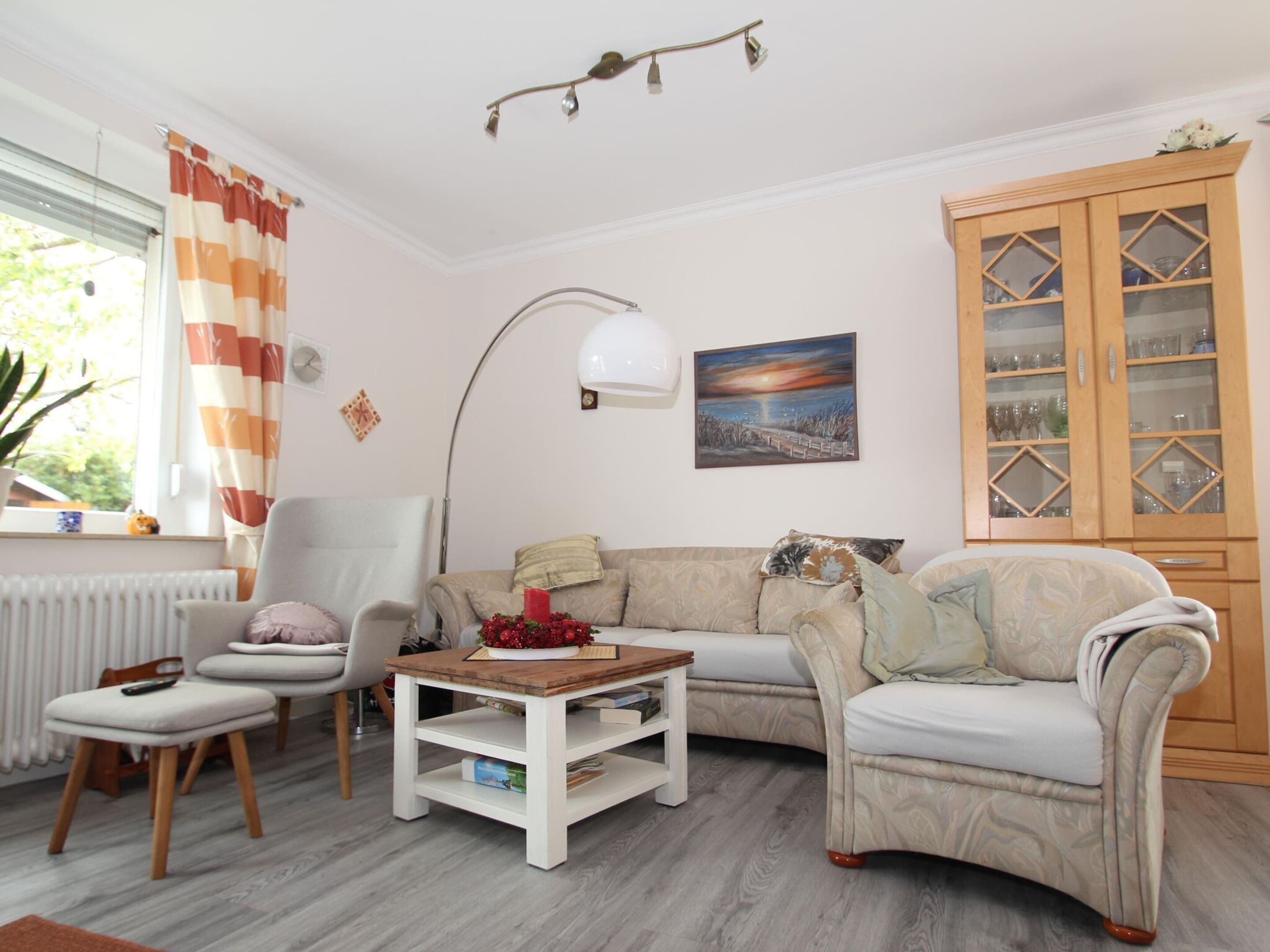 A living room with a sofa, armchair, coffee table, and a cabinet.