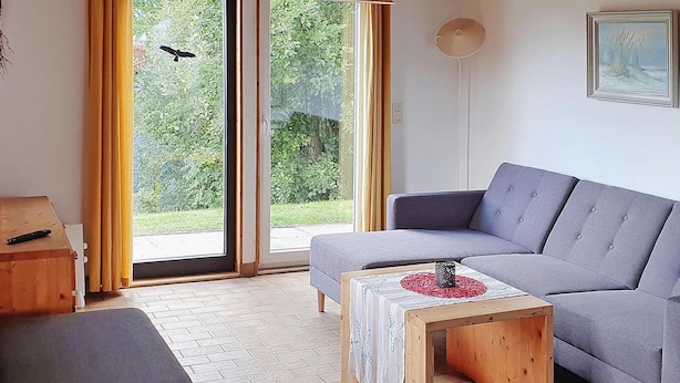 A modern living room with a grey sofa, a wooden coffee table, and a black ottoman. - Ferienhaus am Moenchneversdorfer See, Moenchneversdorf (Schoenwalde am Bungsberg)