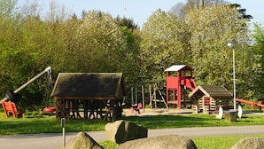 A playground with swings, a slide, and a climbing structure. - Ferienhaus am Moenchneversdorfer See, Moenchneversdorf (Schoenwalde am Bungsberg)