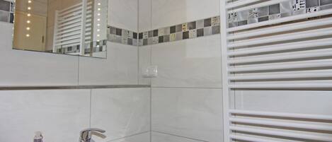 Une salle de bain avec un lavabo blanc, un miroir et un flacon de savon pour les mains parfumé à la mangue exotique de la marque Isana.