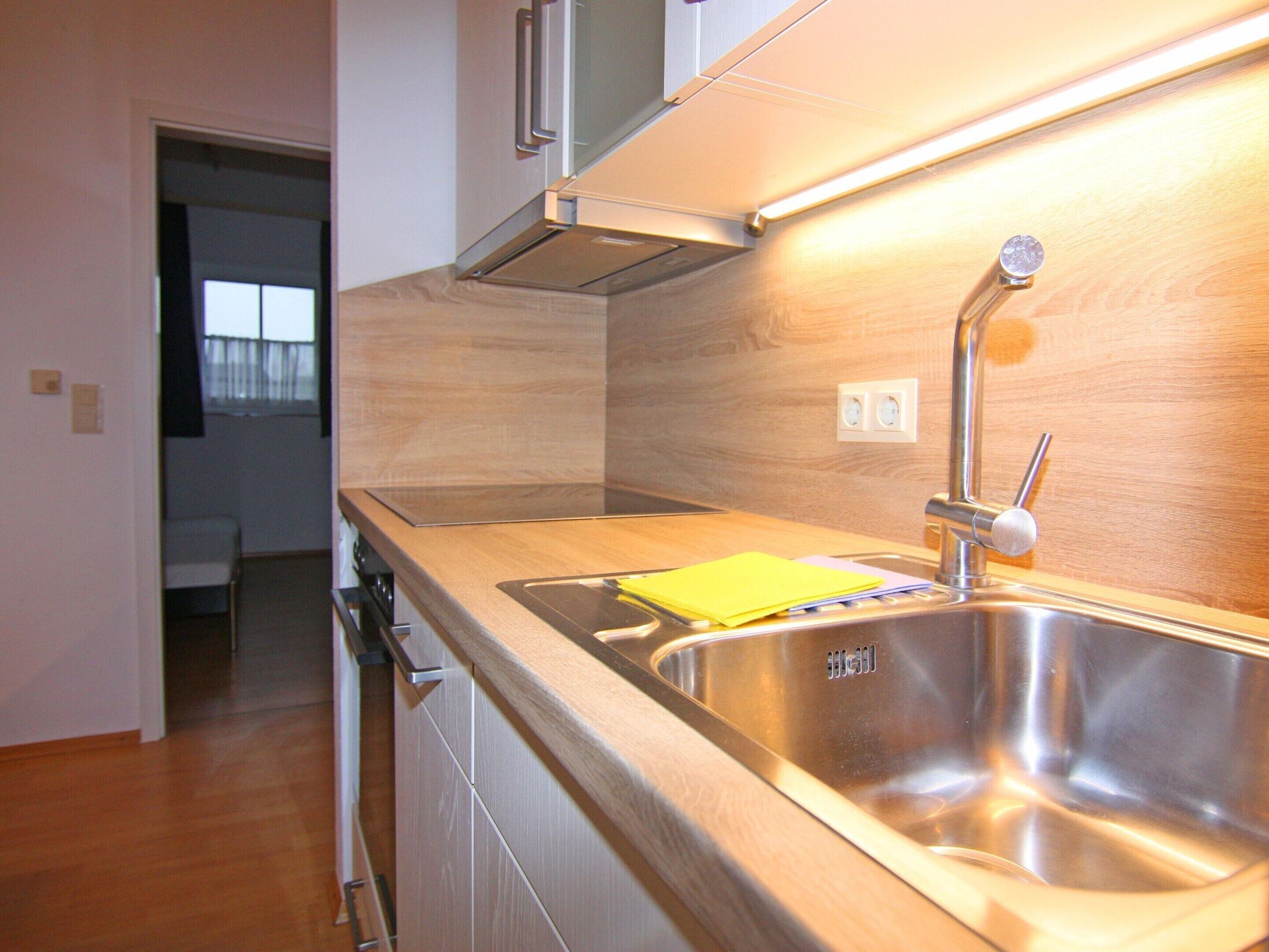 A modern kitchen with stainless steel appliances, a wooden countertop, and a built-in sink.
