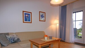 En stue med sofa, sofabord i træ og to billeder hængende på væggen.