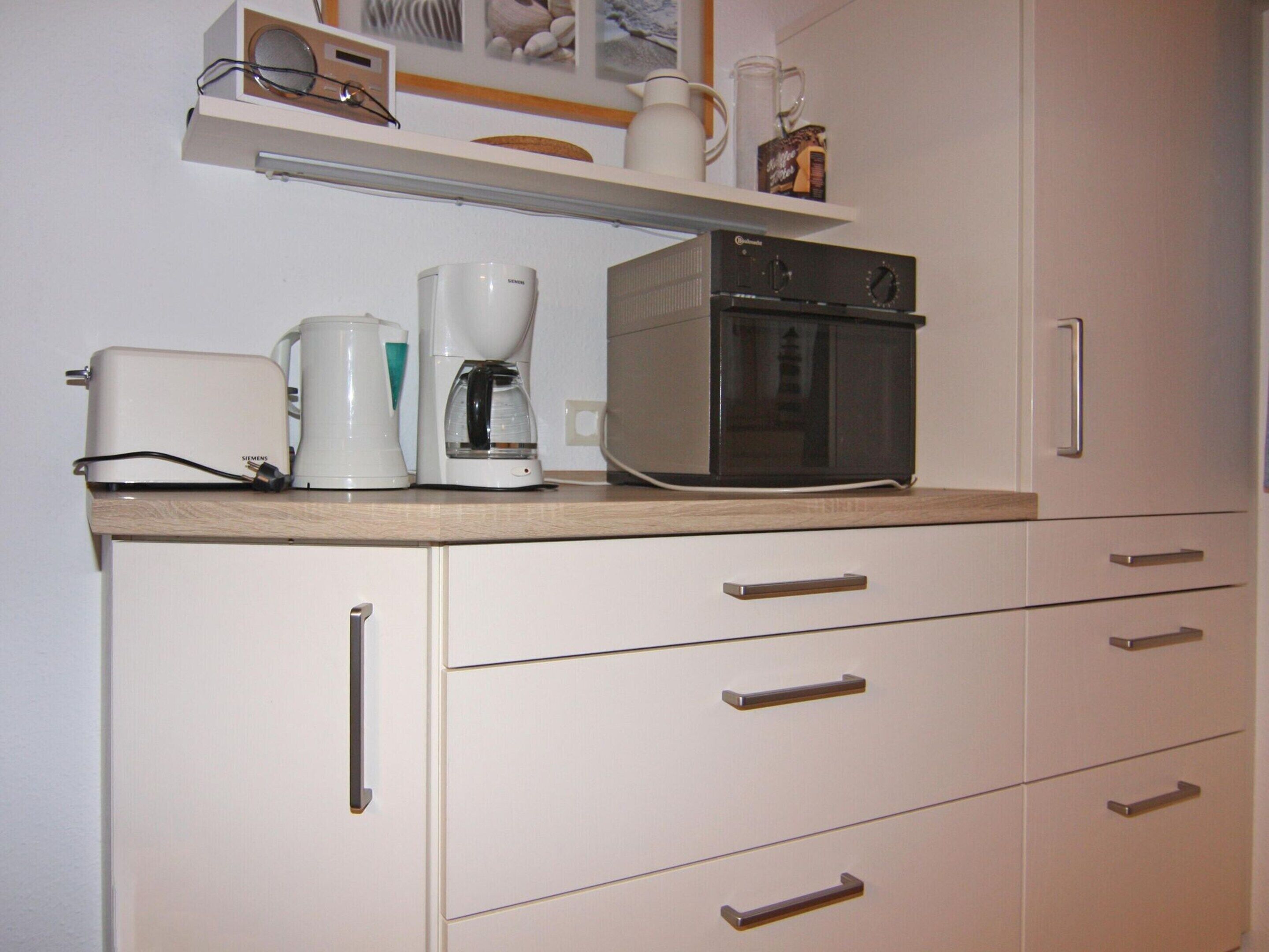 A kitchen with a toaster, coffee maker, and microwave on the counter.