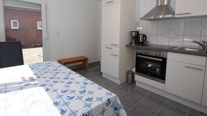 Ett kompakt kök med en inbyggd ugn, en kaffebryggare och en köksfläkt i rostfritt stål.