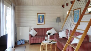 A cozy living room with a red and white checkered sofa, a wooden coffee table, a TV, and a ladder. - Ferienhaus in Lissendorf bei Eifel Wegen (Lissendorf)