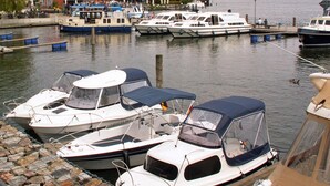 A marina with several boats docked, a red building in the background, and calm water. - Ferienwohnung Seeblick, Malchow (Malchow)