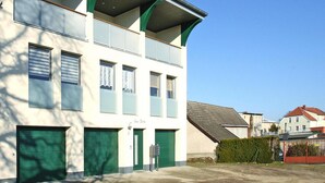 A two-story building with a flat roof, multiple windows, and green garage doors. - Ferienwohnung Seeblick, Malchow (Malchow)