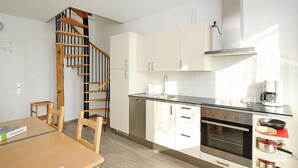 A modern kitchen with white cabinets, a built-in oven, and a stainless steel countertop. - Ferienwohnung Seeblick, Malchow (Malchow)