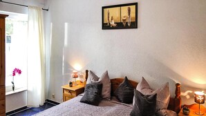 A bedroom with a bed, pillows, a nightstand, a lamp, and a window with curtains. - Wohnung mit Terrasse in Sommersdorf (Sommersdorf)