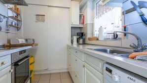 Une cuisine compacte équipée d’un four encastré, d’une machine à café et d’un lave-vaisselle.