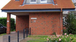 Un bâtiment à deux étages, construit en briques, avec un toit en pente, une petite lucarne et une entrée abritée.
