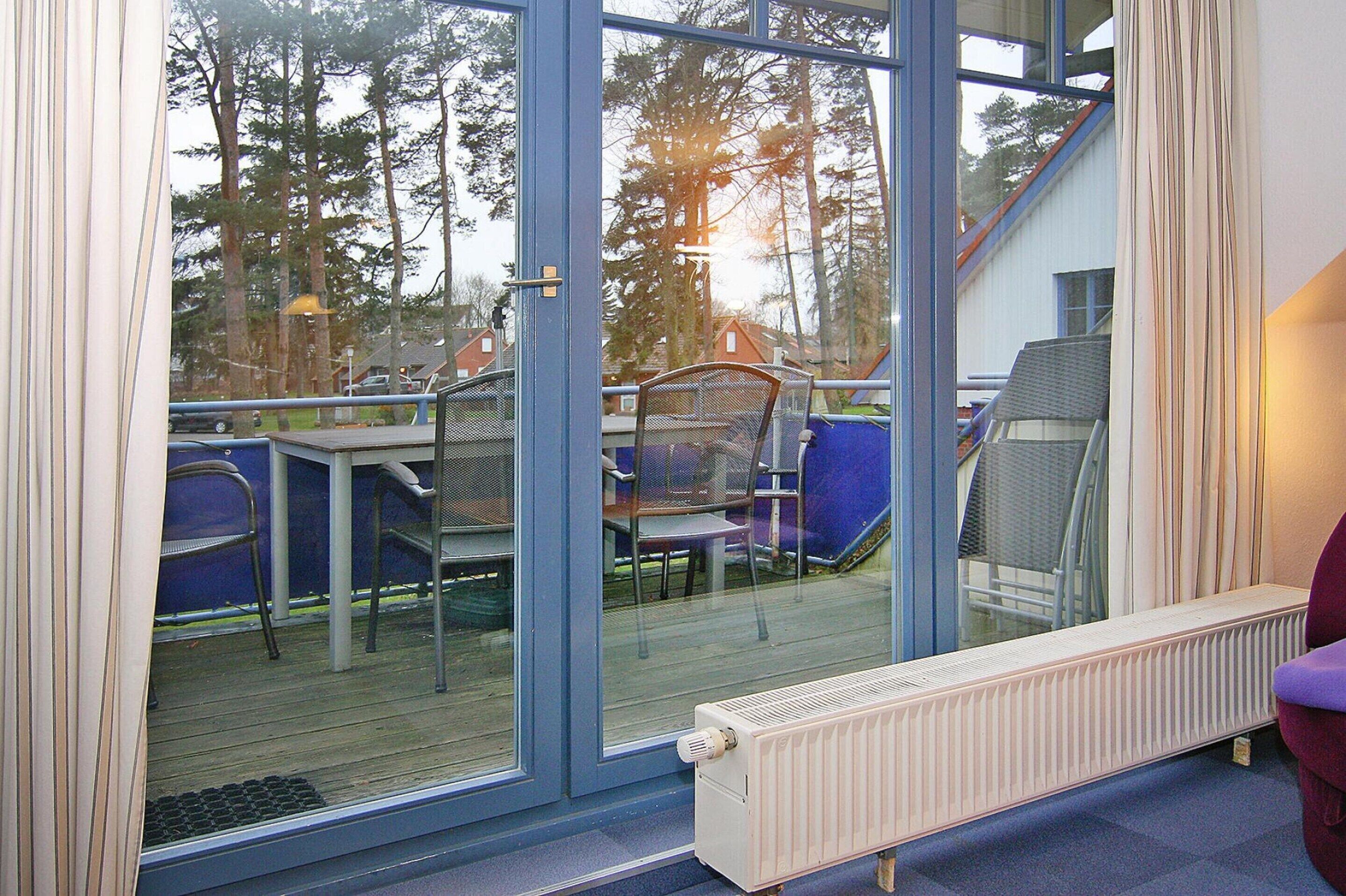 A room with a sliding glass door leading to an outdoor deck with chairs and a table.