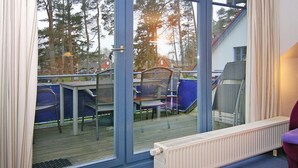 Ein Zimmer mit einer Glasschiebetür, die auf eine Außenterrasse mit Stühlen und einem Tisch führt.