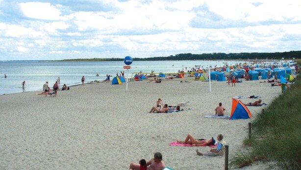Ein Strand mit Zelten und entspannten Menschen.