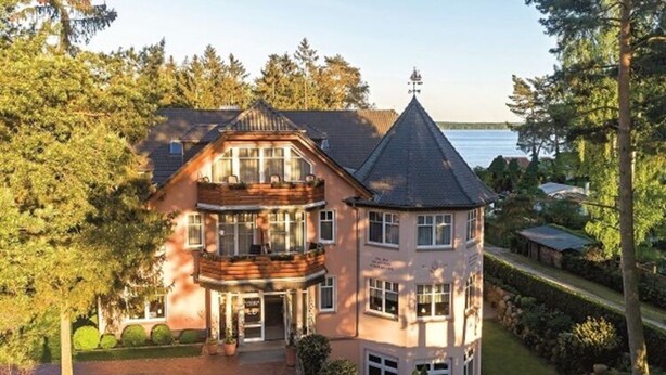 A large, multi-story building with a prominent tower and a bay window. - Seepark Heidenholz, Plau am See (Plau am See)