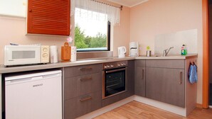 A compact kitchen with a microwave, oven, and coffee maker. - Bungalow Am Spreeufer, Lubben (Lübben (Spreewald))