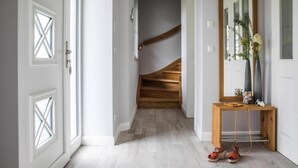Ein Flur mit einer Holztreppe, einem Konsolentisch mit Schuhen und einem Spiegel.