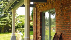 A covered patio with brick walls, a glass door, and outdoor seating. - Ferienhaus, Plau am See (Plau am See)