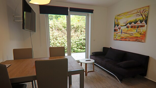 A modern living room with a dining area, a sofa, and a painting on the wall.