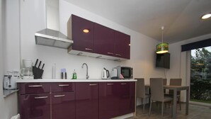 A modern kitchen with dark cabinets, a white countertop, and a dining area with a table and chairs.